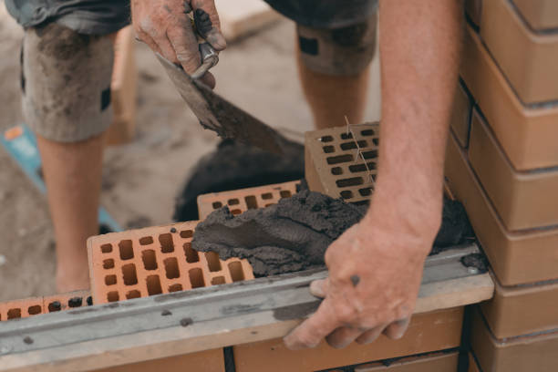 las llanas de albañil untan mortero de cemento sobre ladrillo. albañilería al construir una casa o una cerca de piedra - mason brick bricklayer installing fotografías e imágenes de stock