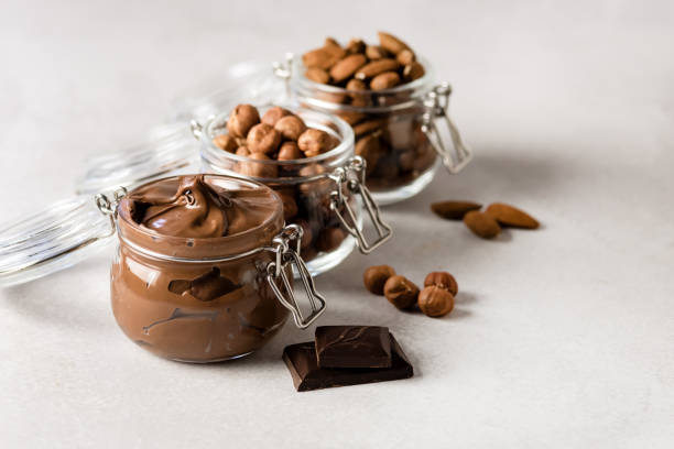 istock Glas Jar with Homemade Chocolate Hazelnut Spread Jars With Nuts Almond and Hazelnut on Light Gray Background Copy Space 1411015414
