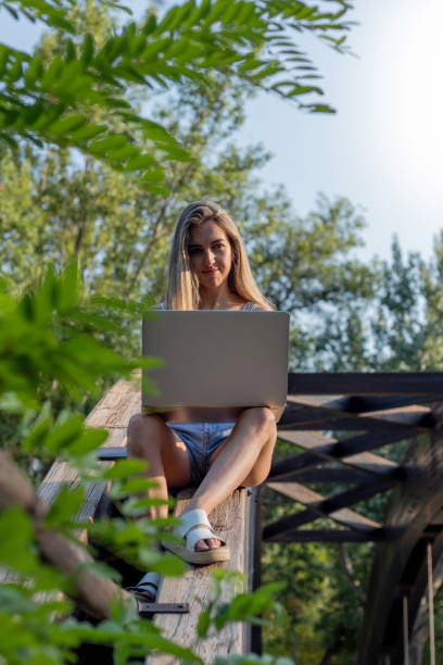 istock Vertical view of young smiling happy woman looking to camera while working as freelancer sorrounded by nature in summer 1411015745