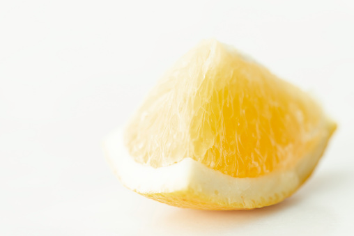 Extreme close up of a lemon slice on white background.