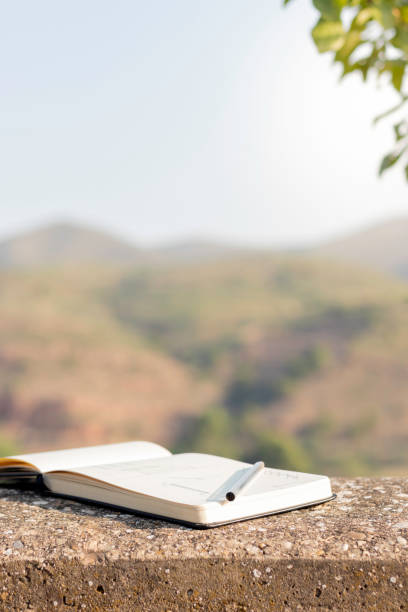 istock Vertical view of isolated open notebook with a pen on it and natural background behind 1411015901