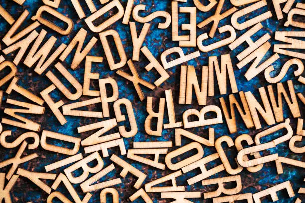 Photo of Wooden alphabet tiles scattered across blue metallic surface