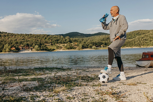 Tired senior man after training, standing and drinking water.