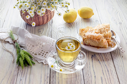 Chamomile tea, milky pie and lemons on a wooden table close-up