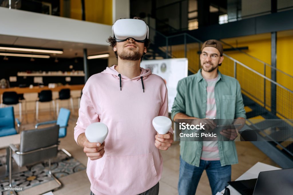 Colleagues testing out virtual reality software Two colleagues at an office working on virtual reality game Gamification Stock Photo