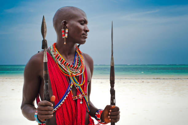 February 2, 2024. Masai Mara National Park. Kenya. Masai warriors stand to meet a car with tourists on the road in the Masai Mara National Park. Kenya.