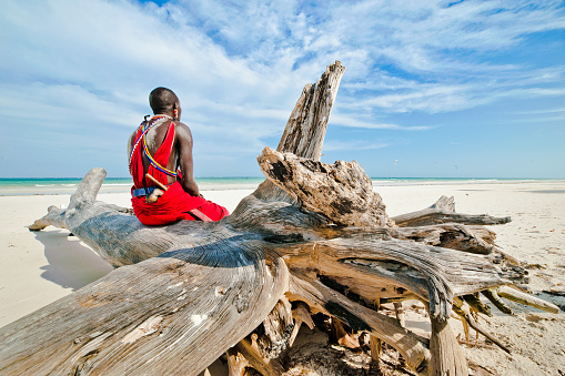 man of the Maasai tribe sits on the shore of the Indian ocean