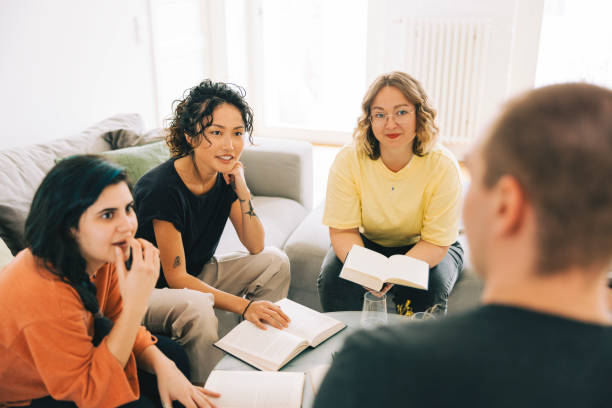 istock Book club members sitting around table at home and talking 1411021574