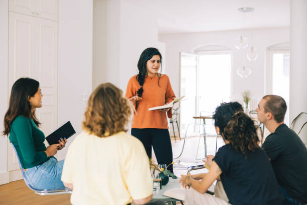 Young woman reading out loud a novel to a group of people in book club stock photo