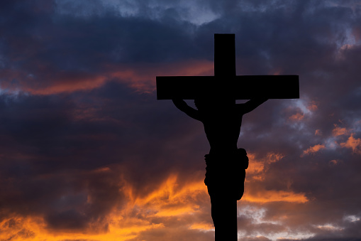 Christ carrying cross up Calvary on Good Friday over dark and stormy sky