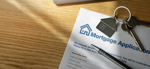 formulario de solicitud de préstamo hipotecario y llaves de vivienda nueva en la mesa de la oficina del banco. espacio de copia photo