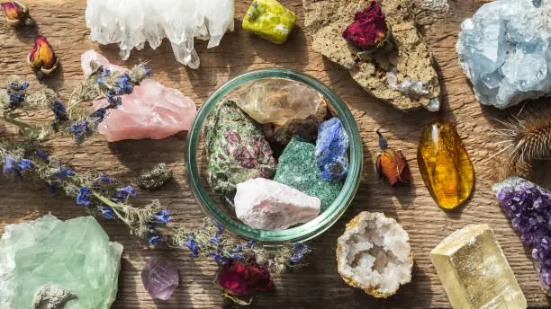 Alternative crystal healing therapy concept. Stones and minerals set up on the wooden table with dry flowers. Gemstones for esoteric spiritual practice or witchcraft