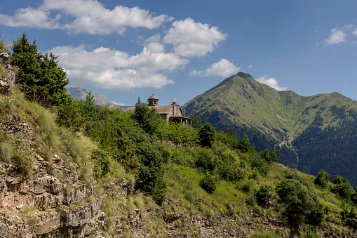 A huge, majestic mountain in the summer on a sunny day and a small church (region Tzoumerka, Epirus, Greece).