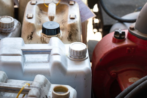 A chemical or fuel oil gallon which is stored at the factory warehouse area. Industrial equipment object, close-up and selective focus at the bottle's cap.