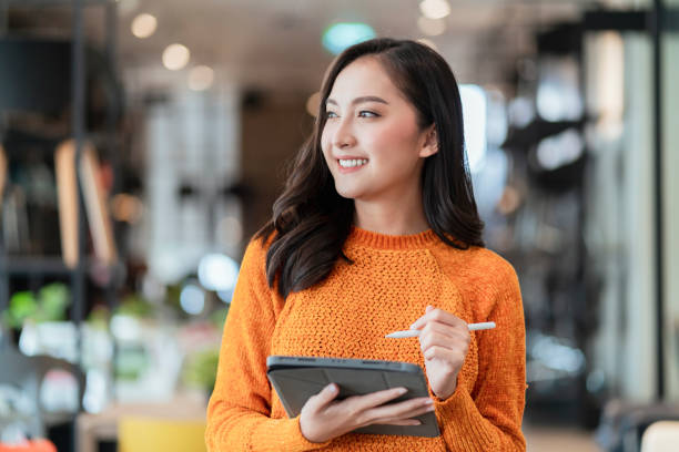 istock asian female smart entrepreneur walk working use tablet device stock manage and checking product inventory in furniture showroom,asian woman smiling cheerful business owner work in furniture store 1411026467