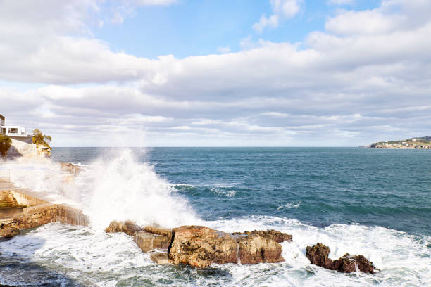 istock Waves breaking on rocks on the shore overlooking a coastal town. Concept vacation 1411026789