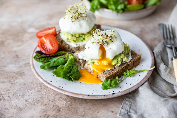 istock Sourdough bread with cream cheese, mashed avocado and poached egg served with salad, tomatoes and sprouts on concrete background. Healthy breakfast or brunch. Diet food concept. 1411027921