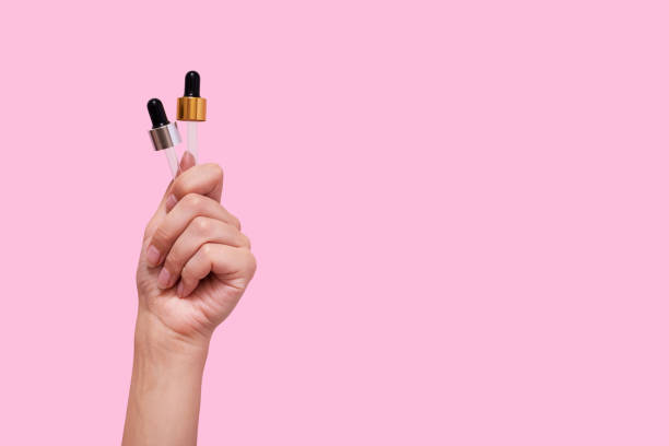 istock Female hand with pipettes on pink color background 1411029516
