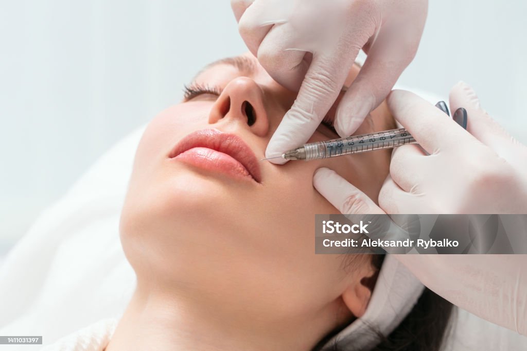 Lip augmentation and correction procedure in a cosmetology salon. The specialist makes an injection in the patient lips. Lip augmentation and correction procedure in a cosmetology salon. The specialist makes an injection in the patient lips Human Lips Stock Photo
