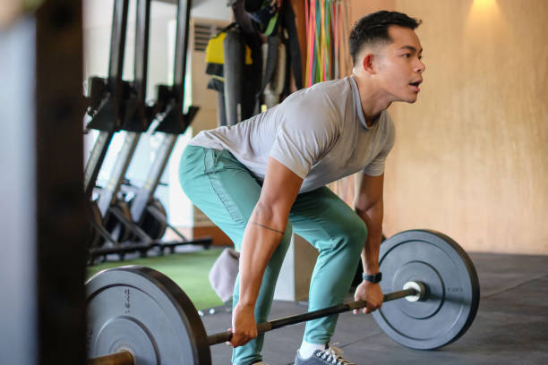 Young Indonesian Man Exercise Deadlift Close-up shot of young Indonesian Man exercise weightlifting using barbel. He's doing deadlift. barbel stock pictures, royalty-free photos & images