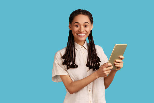 istock Woman working online, using tablet for checking social networks, looking smiling at camera. 1411032740