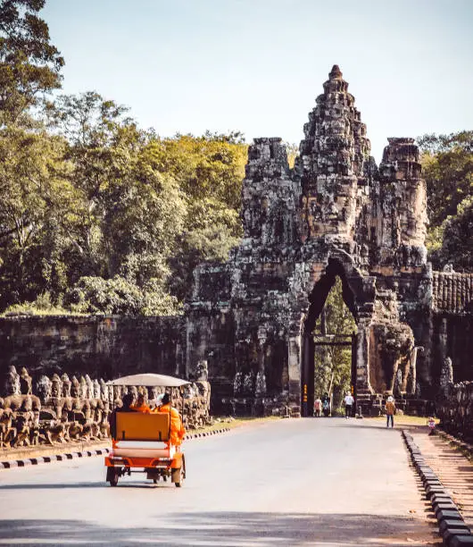 Monks entering a building in the Angkor Wat complex in a tuk tuk