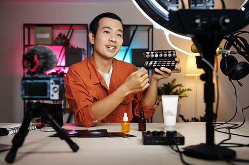 Portrait of young man reviewing new eyeshadows palette for his blog