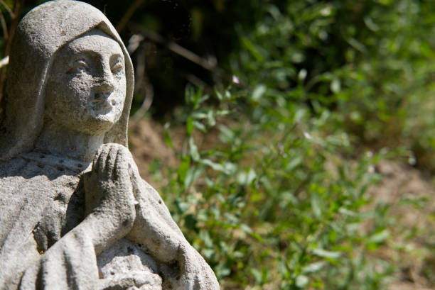 istock ancient stone figure of praying Holy Mary at graveyard 1411034508