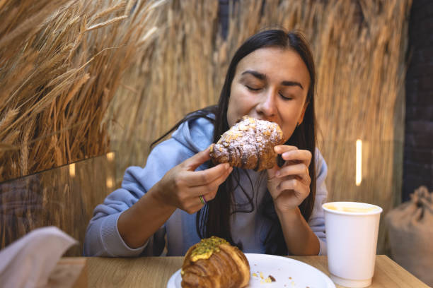 istock A young woman eats croissants with coffee in a cafe. 1411034606