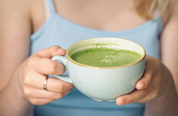 istock Close-up, a cup with green matcha drink in female hands. 1411034880