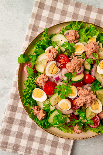 Tuna salad, vegetable salad with quail eggs, lettuce, red onion and cucumbers, on a light gray table, keto food, lifestyle, healthy eating, selective focus, top view, no people,