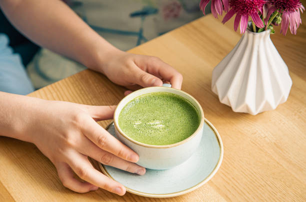 istock Close-up, a cup with green matcha drink in female hands. 1411034899