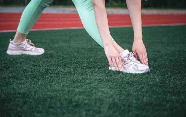 istock A young woman stretches before jogging while sitting in the stadium. 1411034933