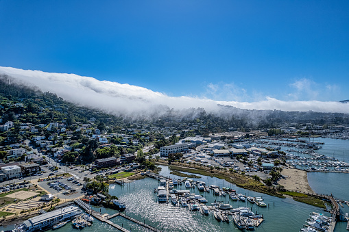 Aerial view of Sausalito on a sunny day with fog rolling over the hillside. View of Bay and marina.