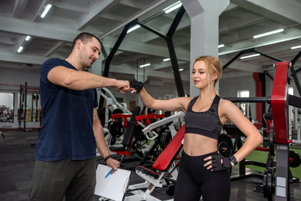 istock Personal male instructor helping woman doing exercise with heavy dumbbells 1411037379