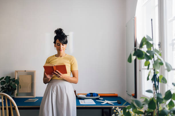 istock A Happy Intelligent Woman Reading While Standing Leaned On The Desk 1411043503