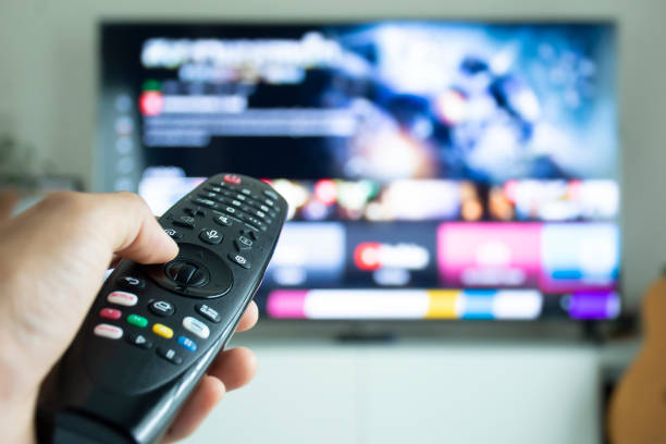 Hand holding a remote to browse TV shows or series. stock photo