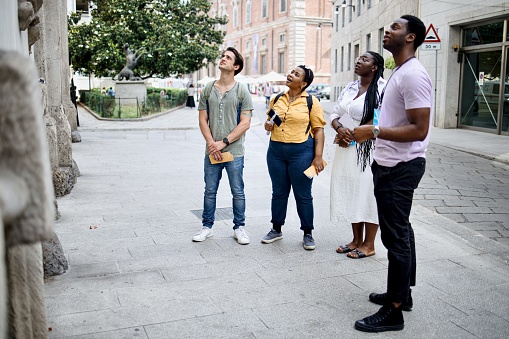 A group of multiracial people have a tour guide as they explore the city of Milan