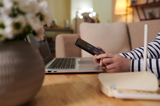 Hands of young woman installing smart home application on smartphone