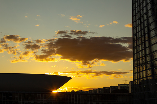 Brasília, Federal District, Brazil – July 23, 2022:  Detail of the building of the National Congress of Brasilia in silhouette with sunset in the background in the late afternoon. Sky with yellowish tones.