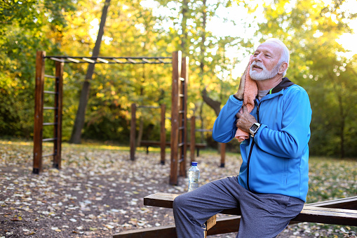 Senior man relaxing after exercising in an autumn park. About 65 years old, Caucasian male.