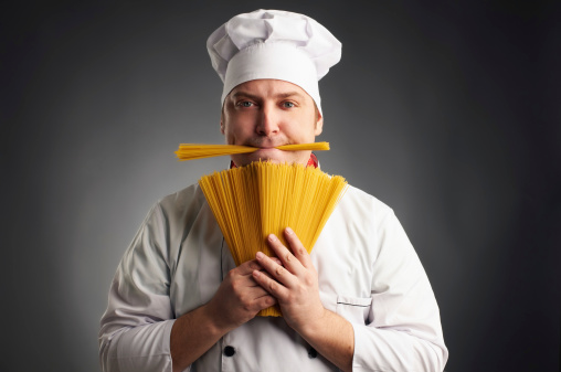 funny cook with spaghetti in his mouth on grey background