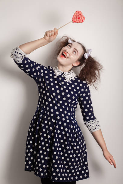 fun girl with bright makeup and red lollipop on white background smiling