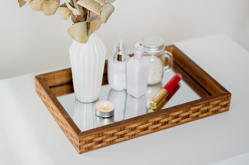 Skin care products and candle on mirror tray. Aesthetic minimalist composition.