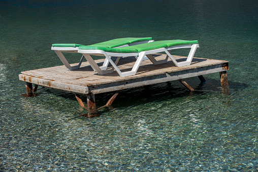 White, wooden chair on dock and beautiful lake view.