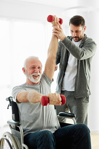 Doctor or nurse or physiotherapist caregiver exercise with senior man at clinic or nursing home