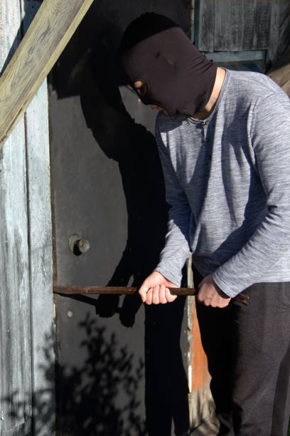 istock a thief in a black mask breaks down the door with a crowbar 1411057650
