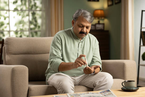 Senior man checking blood sugar level at home stock photo stock photo