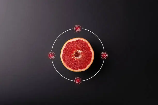 Half a grapefruit on a black background, top view and with icons around
