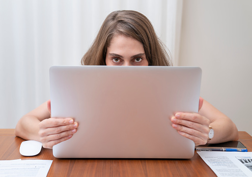 Woman using laptop while sitting at home. Woman working on computer in her home office during pandemic quarantine.